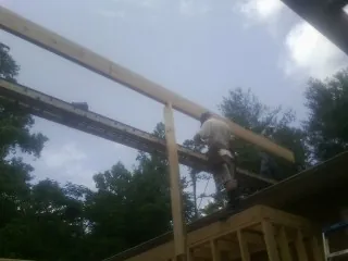 Carpenter setting a ridge beam over a new addition frame — Ice Dam Removal by Roofing Brothers in Norwood