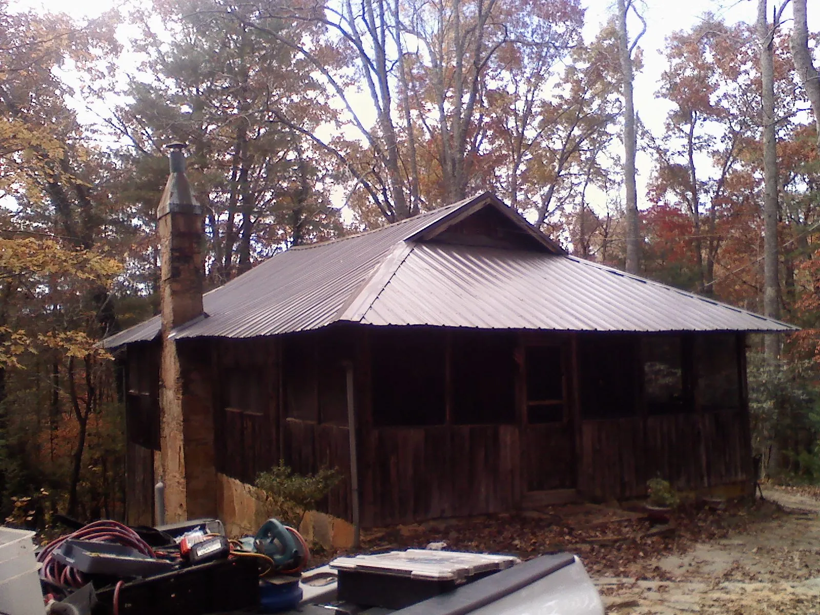Brown metal hip roof on an old cabin with a stone chimney in Norwood