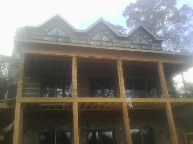 Dormers and porch framing on a large log home under construction — Roof Coating work by our crew in Norwood