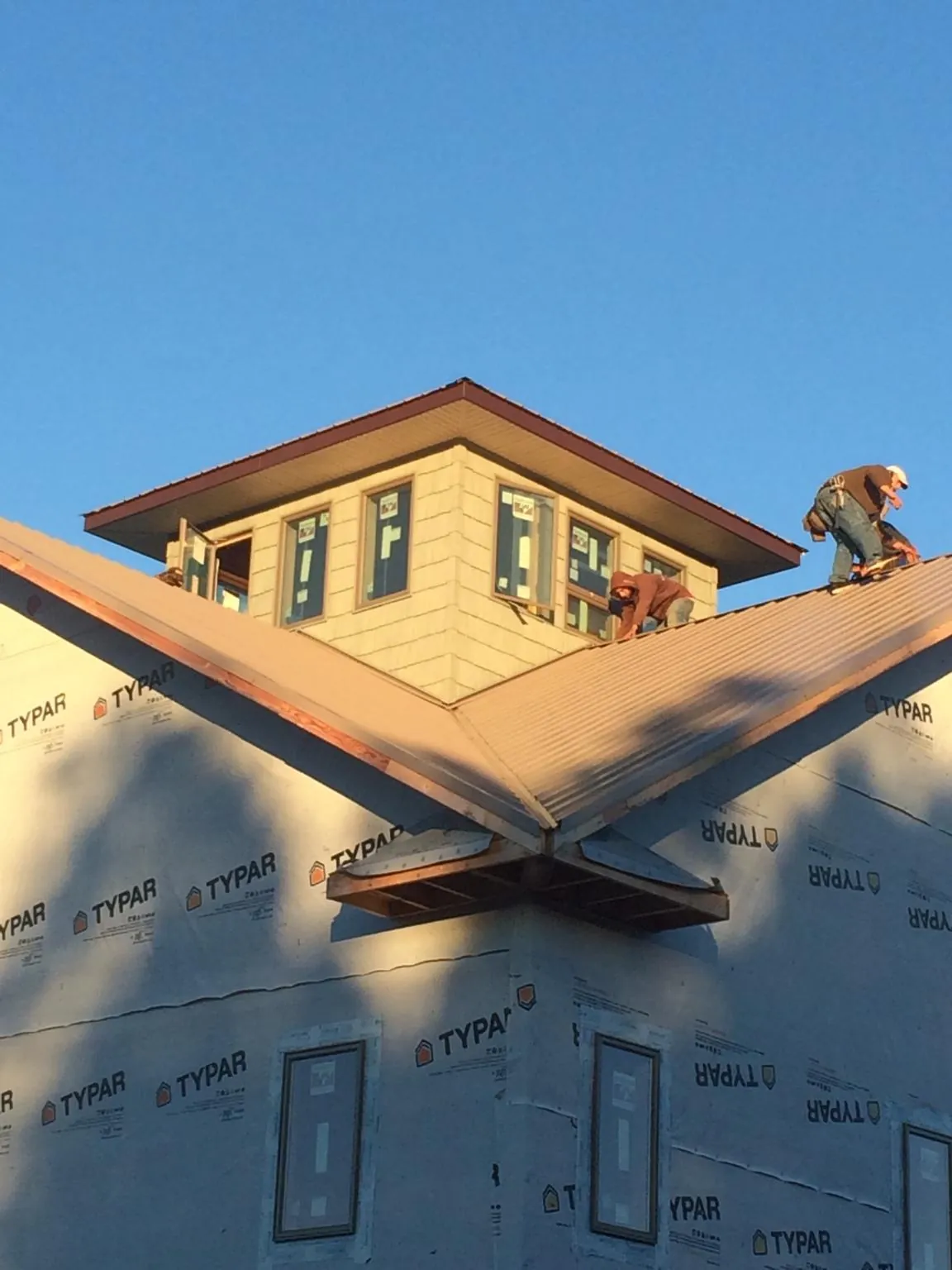 Roofers working around a rooftop cupola on a new metal roof at sunset — Roof Waterproofing in Norwood by Roofing Brothers
